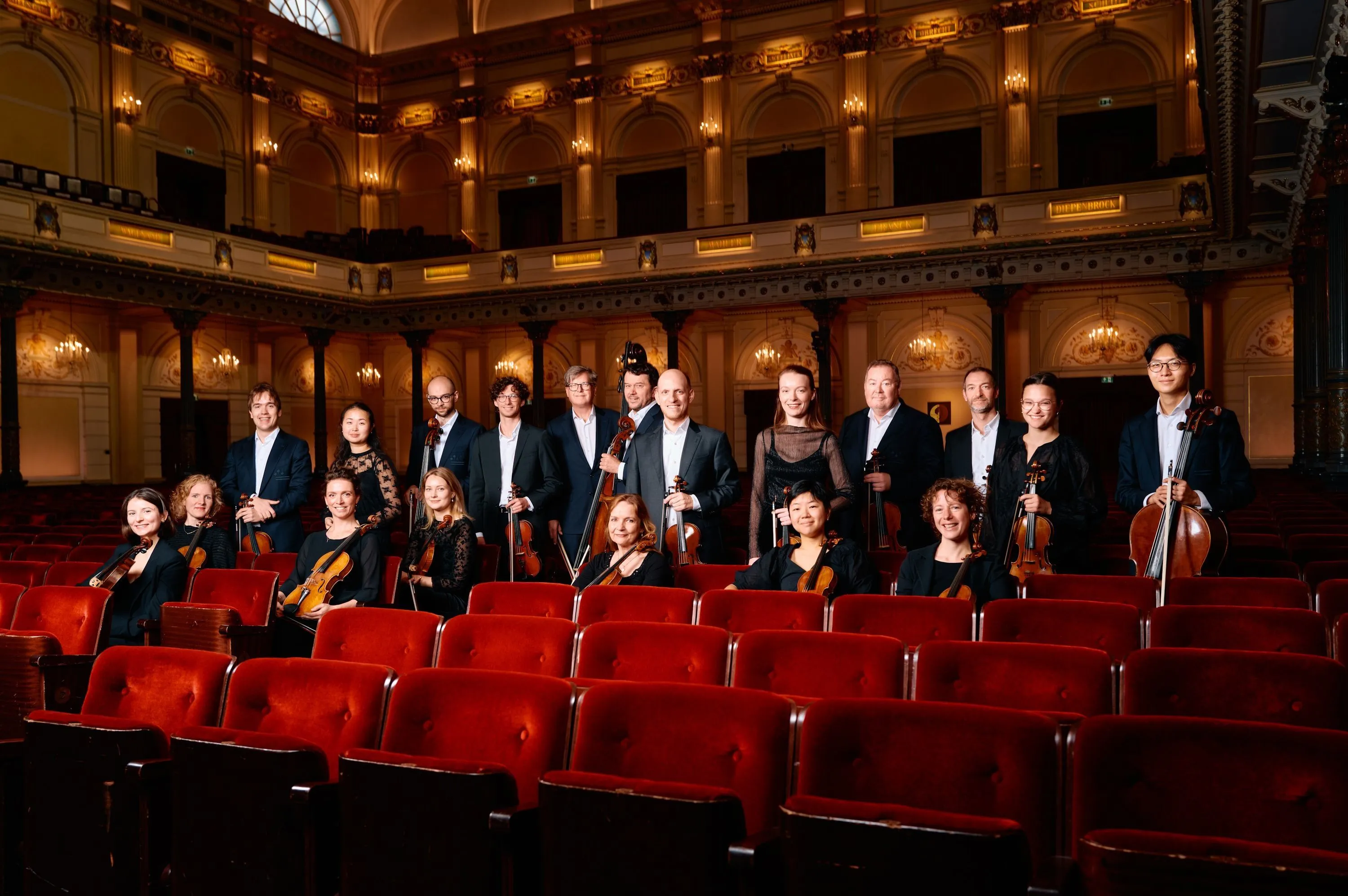 Members of the Concertgebouw Chamber Orchestra with their instruments among the red seats of the Concertgebouw's main hall