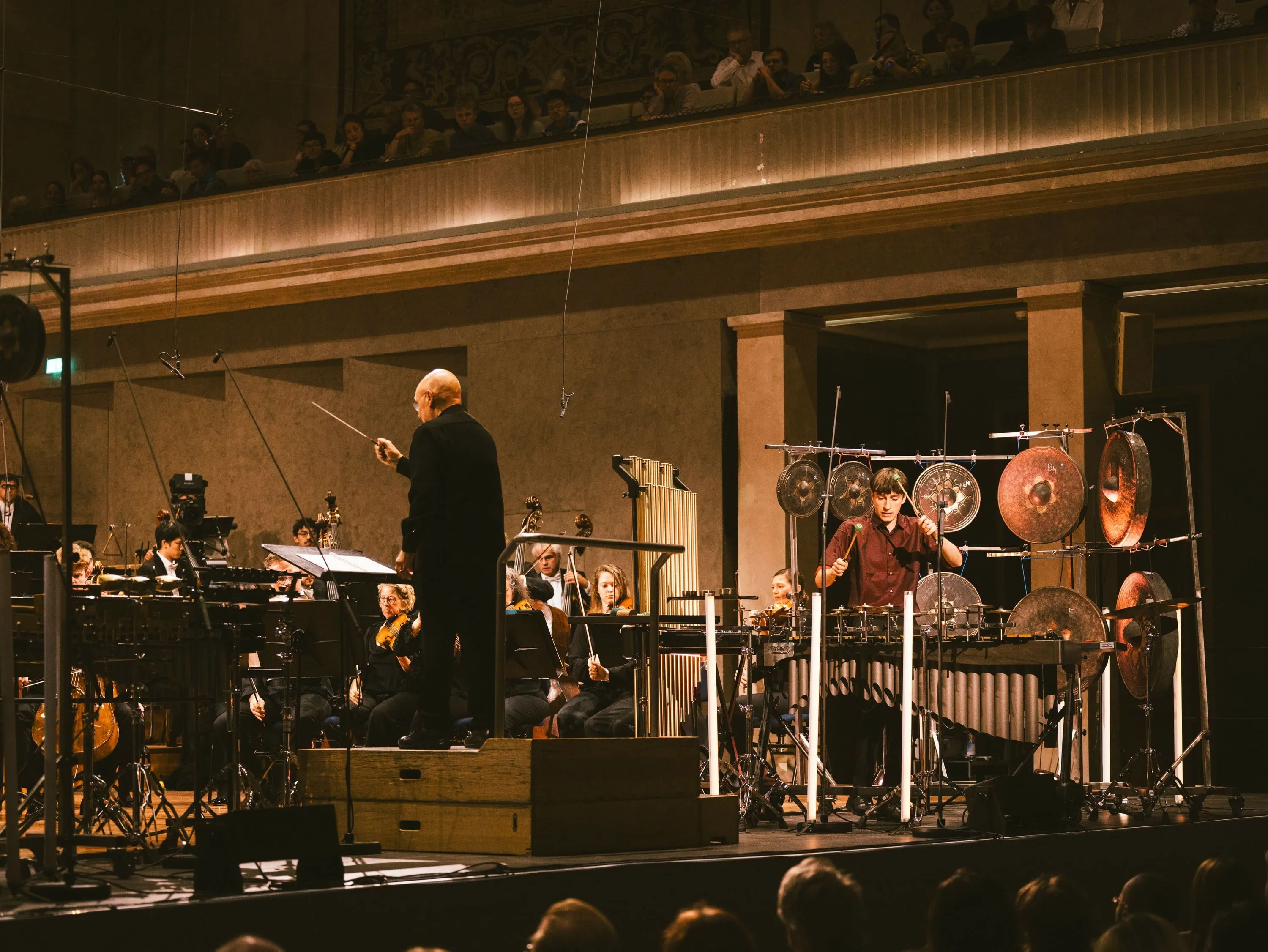 Gabriel Michaud performing among his percussion instruments with an orchestra and conductor Dennis Russell Davies at the Herkulessaal in Munich
