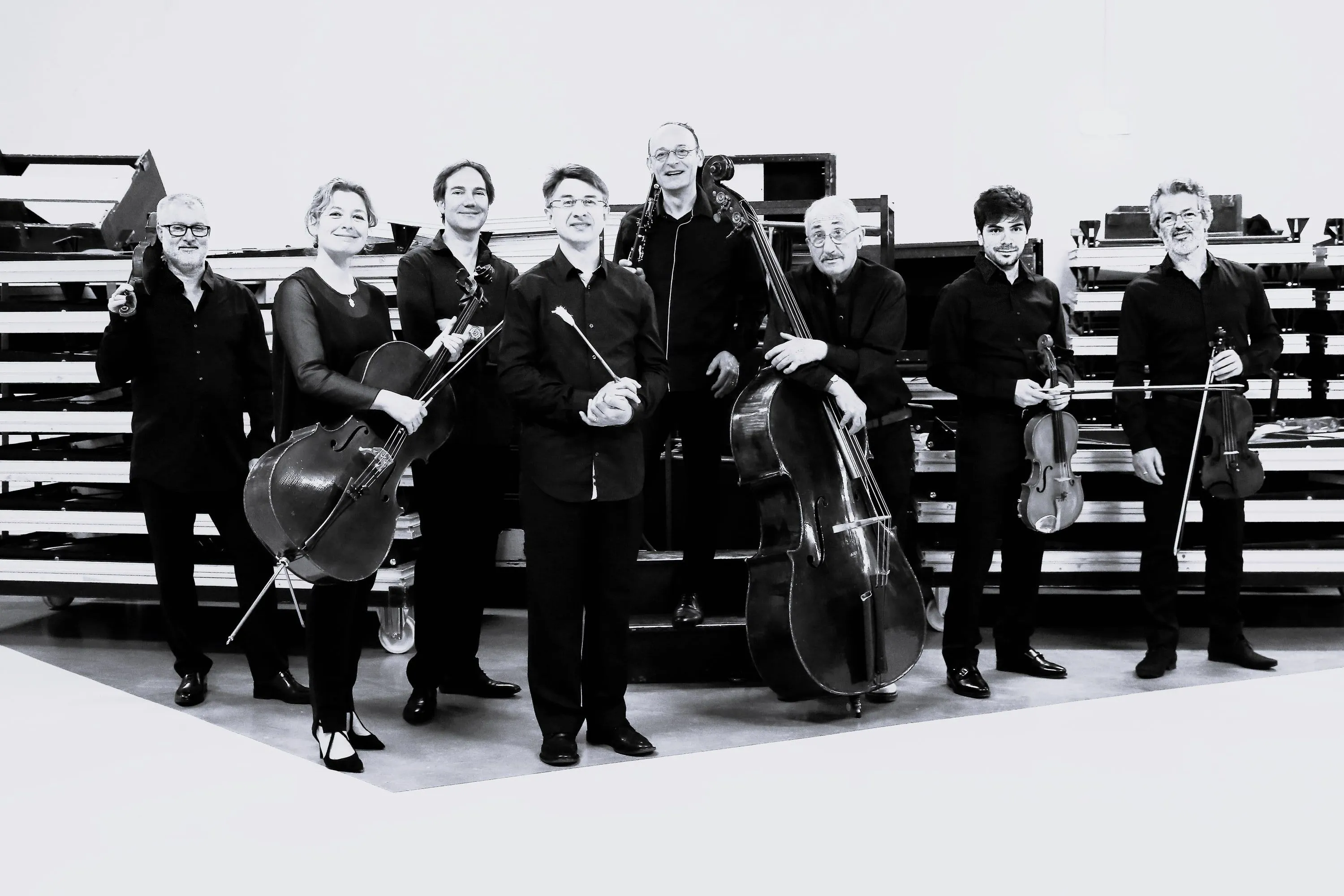 The eight musicians of the Sirba Octet standing with their instruments in a black-and-white group portrait
