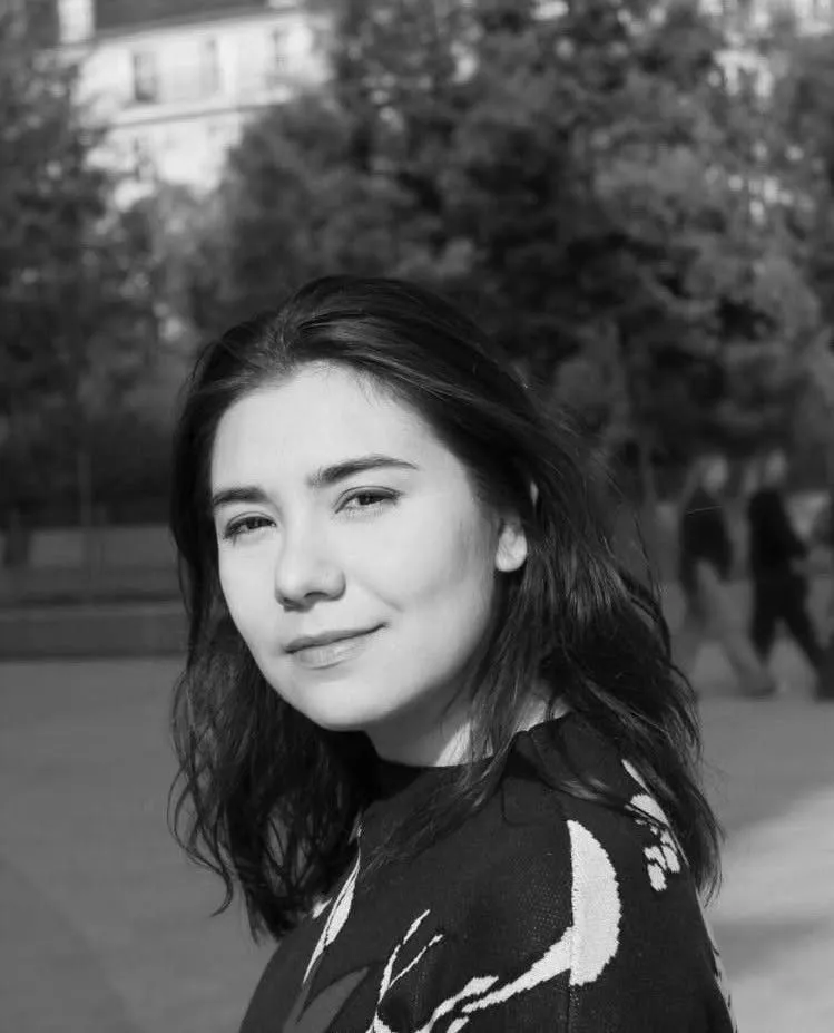 Irène Mejia smiling over her shoulder outdoors in Paris, black-and-white portrait
